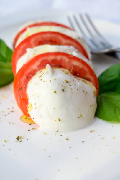 istock Caprese salad made with fresh soft white italian cheese mozzarella buffalo, green basil, red tomatoes and origano herb 1299842348