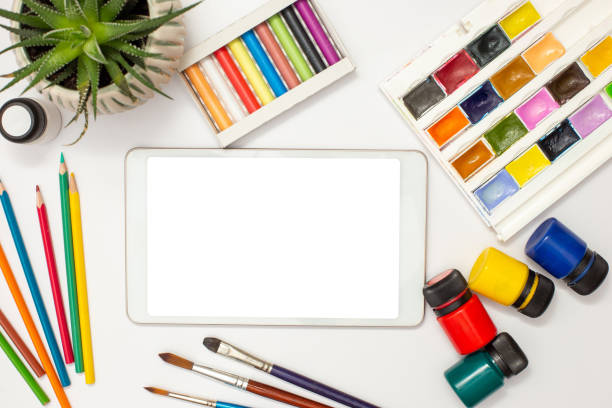 istock White digital tablet with a blank screen on a white table with multicolor drawing supplies and brushes. 1299843158