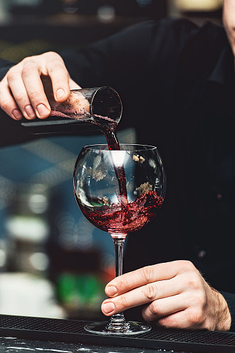 Barman pouring vine into glass in detail
