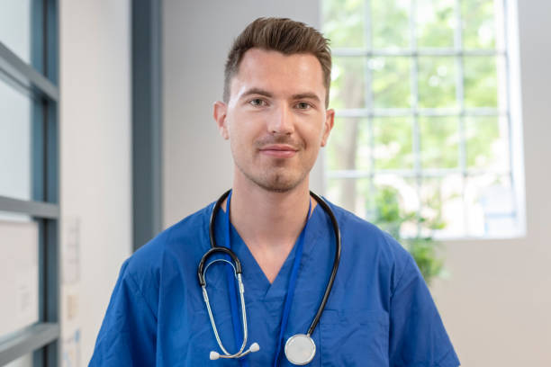 Portrait of smiling male nurse A male medical professional wearing scrubs smiles directly at the camera while at work in a medical clinic, hospital or assisted living care facility. self sacrifice stock pictures, royalty-free photos & images
