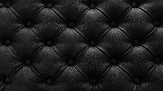 Black background. Stylish soft black leather upholstery of sofa. Black material is decorated with leather buttons.