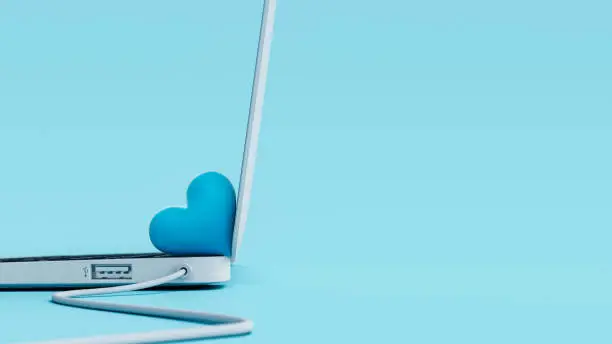 Photo of Laptop computer with small blue heart. Online dating concept background