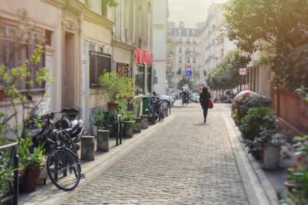 kobieta idąca alejką w słoneczny dzień - paris street zdjęcia i obrazy z banku zdjęć