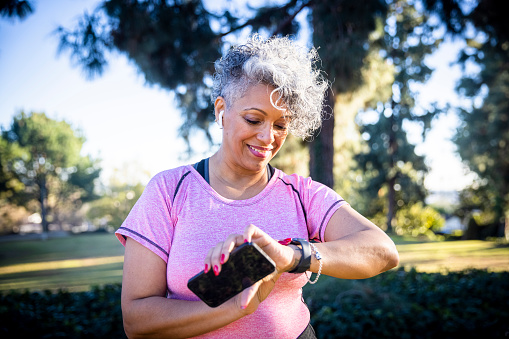 A beautiful black woman running with a fitness tracker.