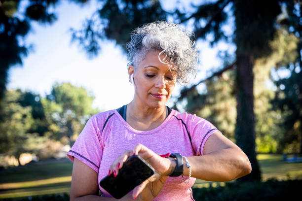 senior black woman läuft mit einem fitness-tracker - fitness tracker stock-fotos und bilder