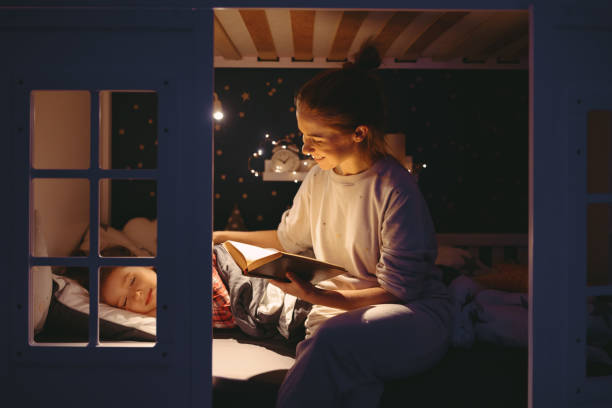 istock Mother reading book to sleeping daughter 1299850376