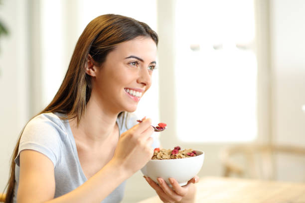 istock Happy woman eating cereals from bowl for breakfast 1299850620