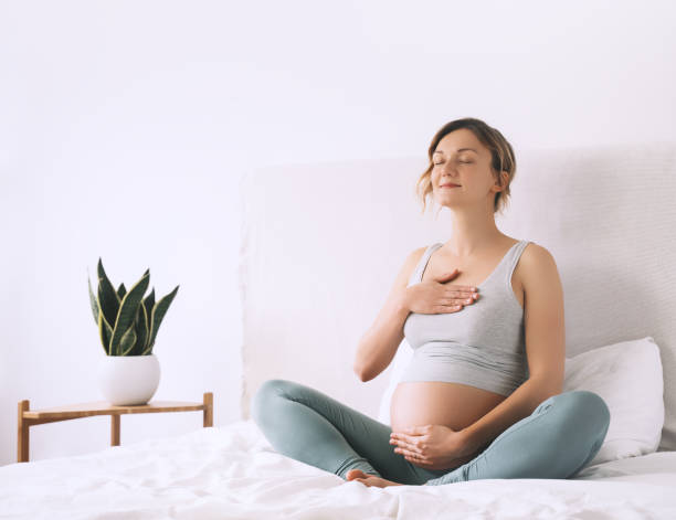 mujer embarazada en pose de loto haciendo meditación o ejercicios de respiración para un embarazo saludable y preparando el cuerpo para el parto. - human pregnancy yoga exercising prenatal care fotografías e imágenes de stock