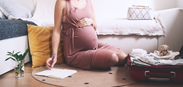 istock Pregnant woman packing bag for maternity hospital, making notes, checking list in diary. 1299850699