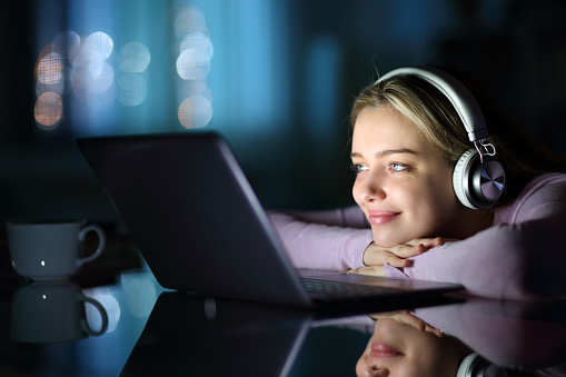 Teen wearing headphones watching media on laptop