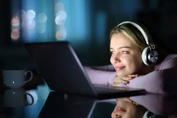 Photo of Teen wearing headphones watching media on laptop