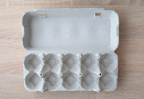 Cardboard egg box. Empty egg carton. Eggs box. Empty box of 10 eggs on a wooden table