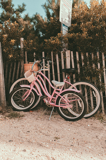 A pair of colorful bicycles lean against a wooden fence, left by their owners who took the sandy path up to the beach.