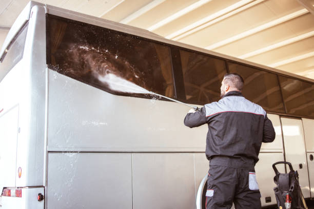 bus get washed manually by worker with a water jet in garage - manually imagens e fotografias de stock