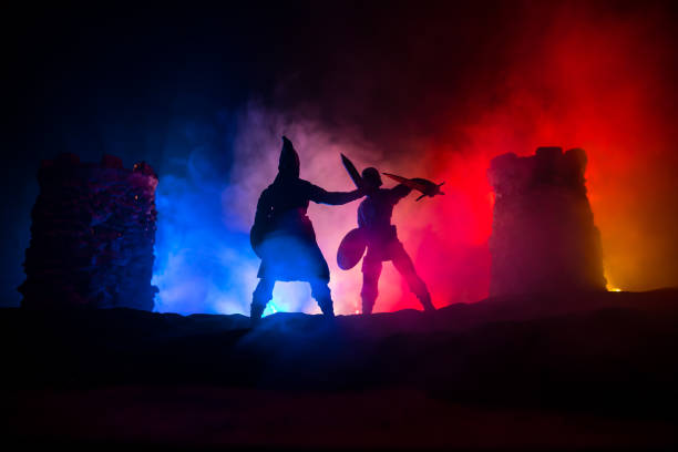 istock Medieval battle scene. Silhouettes of figures as separate objects, fight between warriors at night. Creative artwork decoration. Foggy background. 1299855108
