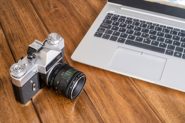 istock An old 35 mm reflex camera on a wooden table next to a modern laptop, a contrast between modern and old 1299857148