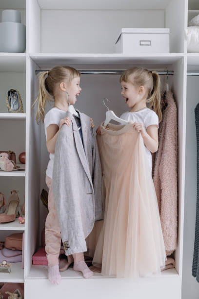 Twin Girls Try On Things in Their Mother's Modern Dressing Room. stock photo