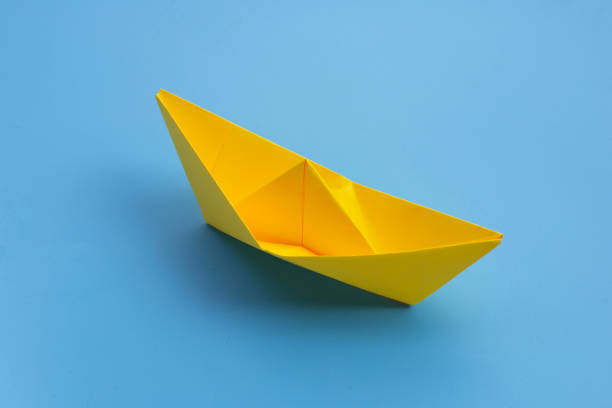 istock Yellow paper boat on blue background. 1299858776