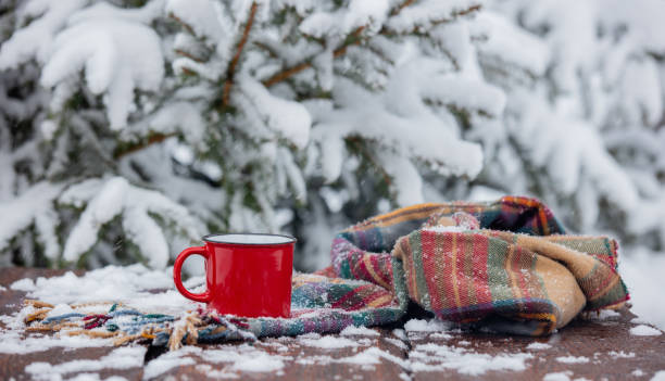 istock Red cup of coffee and scarf on wooden table in blizzard 1299861817