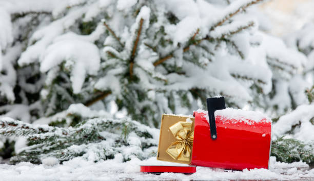istock Red mailbox with gift box inside on wooden table in snow 1299861832