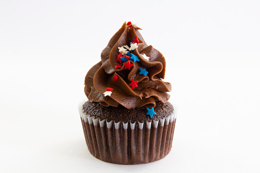 A double chocolate cupcake with red, white and blue star sprinkles.
Isolated on a white background.