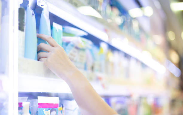 Female  hands holding body lotion on the shelf of cosmetic at the department store stock photo