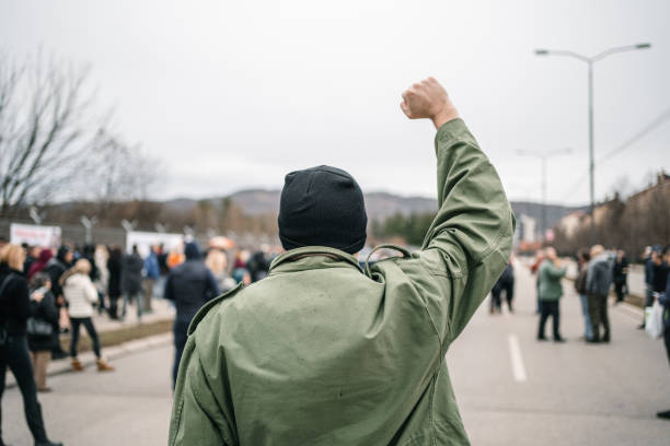 istock Unrecognizable man with raised fist during a protest in a street 1299865538