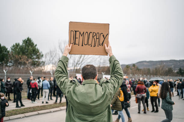 istock Protestor on a street holding a placard with text Democracy 1299865711