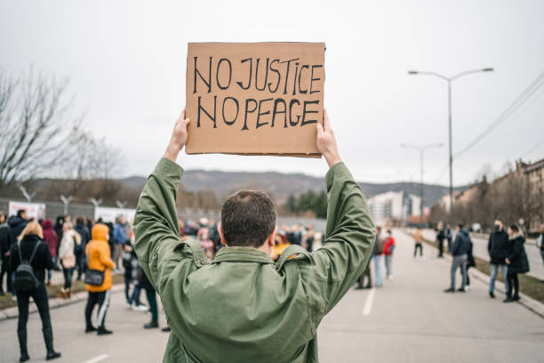 istock Protestor on a street holding a banner with text No justice no peace 1299865778