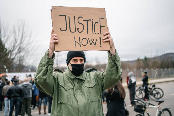 istock Man with protective mask holding a placard with text Justice now 1299865800