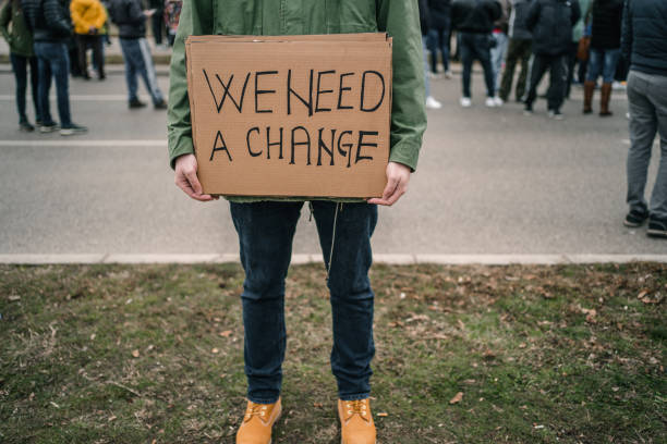 istock Unrecognizable man holding a banner with text We need a change 1299865872