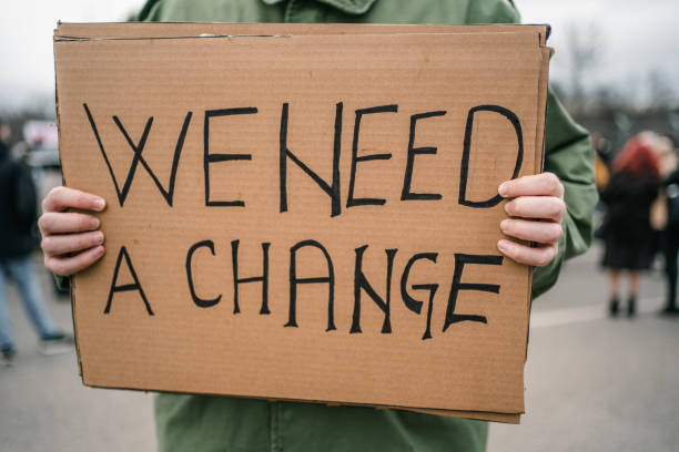 istock Man holding a banner with text We need a change during a protest 1299865876