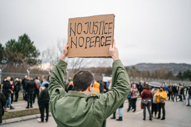 istock Unrecognizable man protesting on a street holding a banner with text No justice no peace 1299865888
