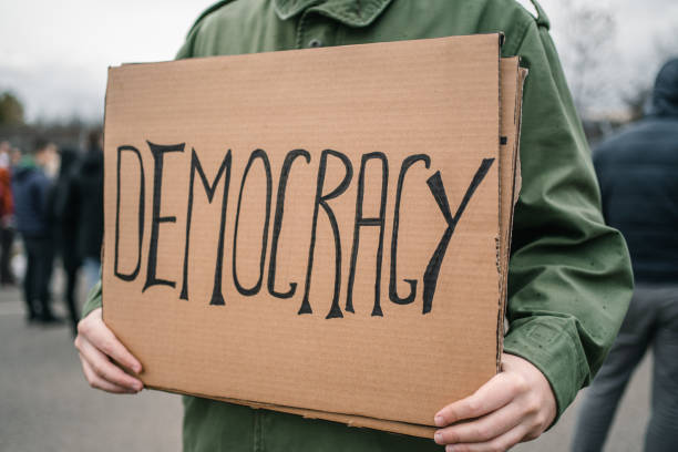 istock Protestor holding a sign with text Democracy on a street 1299866407