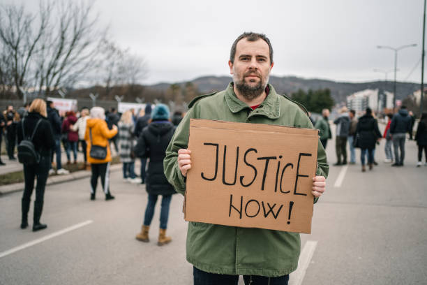 istock Man protesting on a street holding a placard 1299866576