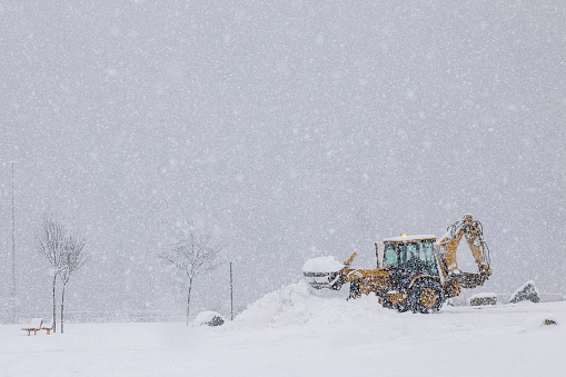 Yellow snowplow removing snow during blizzard in countryside village in Canada, British Columbia, Pemberton
