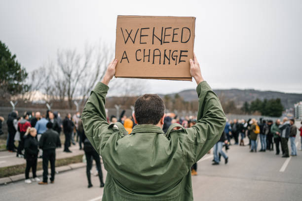 istock Man protesting on a street holding a banner with text We need a change 1299866609