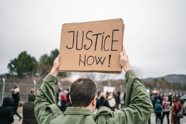 istock Protestor on a street holding a placard with text Justice now 1299866668