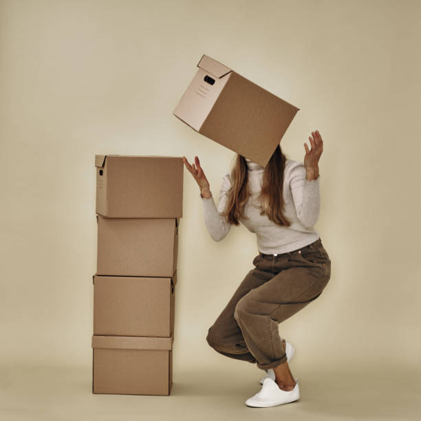 istock A cardboard box falls from the girl's hands. Moving and packaging, environmentally friendly materials 1299866699