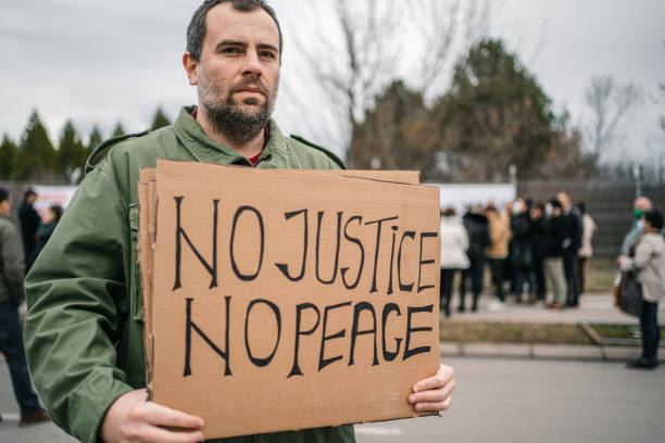 istock Man protesting on a street holding a placard 1299866773