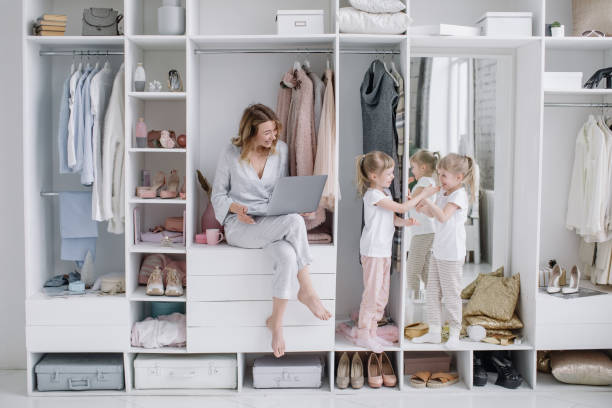 Young mother with her twin daughters choose things online in the comfort dressing room stock photo