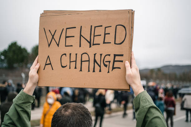 istock Man holding a sign with text We need a change 1299867316