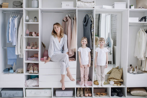 Young mother and her twin daughters are in their modern dressing room looking at the camera stock photo
