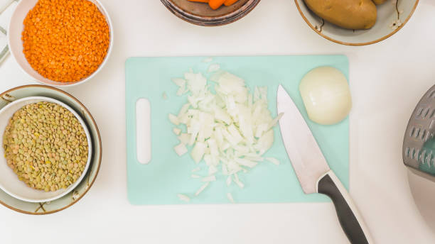 recette de soupe aux lentilles. fin hachée d’oignon vers le haut sur la planche à découper - carrot close up silverware cutting board photos et images de collection