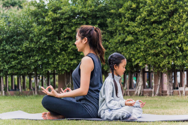 istock mother practicing doing yoga exercises with her daughter outdoors in meditate pose together 1299873895