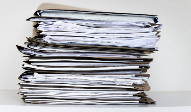 istock Extremely Close up Stack of Documents Folders on Office Desk Waiting to be Completed 1299874107