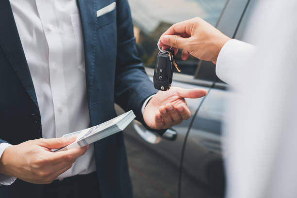 Closeup hand giving a car key and money for loan credit financial, lease and rental concept stock photo