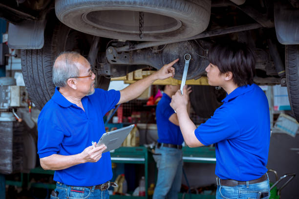 istock Engineer car mechanics pose checking under car by see detail document on hand to maintenance and fixed car in garage. 1299885684