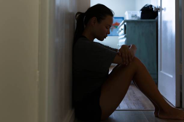 istock Depression. A sad woman sitting alone at home on the floor. 1299887980