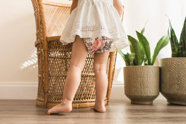 22-Month-Old Toddler Girl Standing While Wearing a Vintage Floral Modern Reusable Cloth Diaper and a White Shirt 22-Month-Old Toddler Girl Standing While Wearing a Vintage Floral Modern Reusable Cloth Diaper and a White Shirt with a Neutral Wood Background in Bright Natural Light pics of girls buttocks stock pictures, royalty-free photos & images